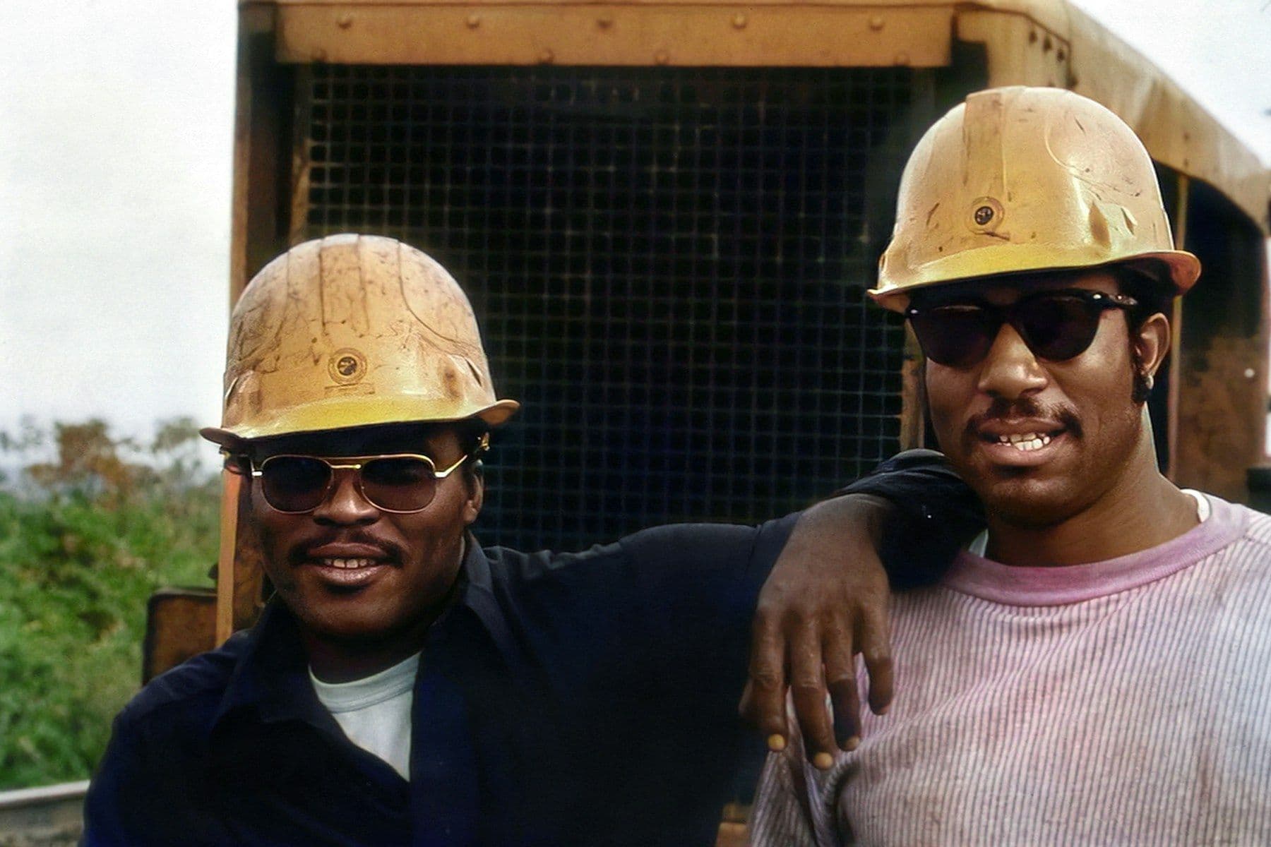 Two men in hard hats smiling on a job site
