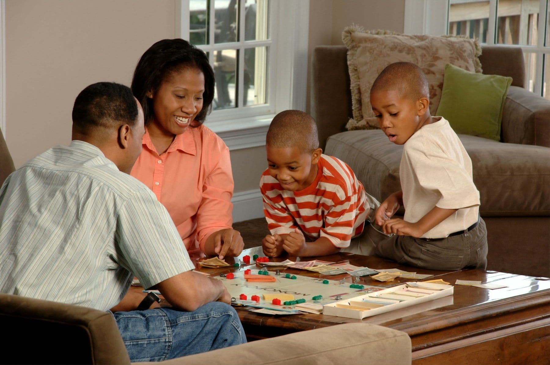 A Black family playing a board game together in their living room