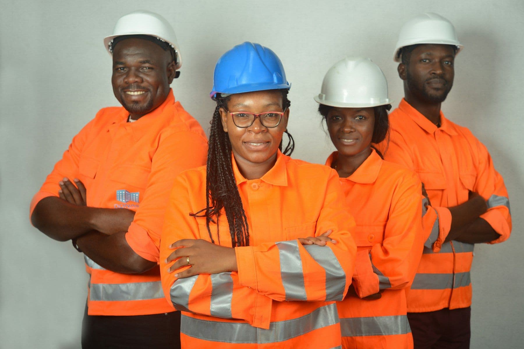 Workers in orange safety jackets and hard hats smiling together