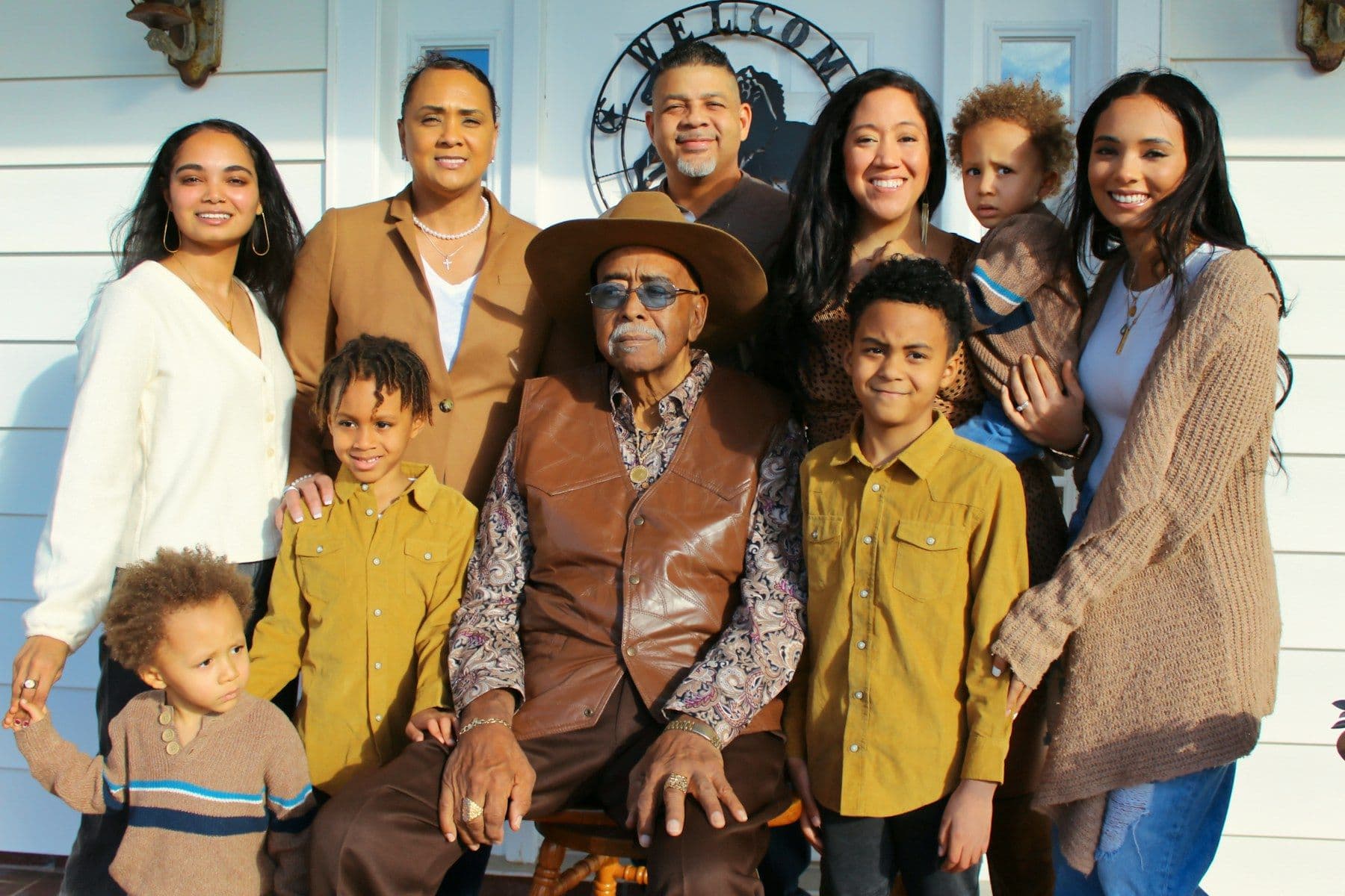 A multigenerational Black family posing together outside their home